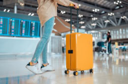 Eine Frau mit Koffer am Flughafen – Vielflieger-Tipps.
