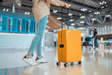 Eine Frau mit Koffer am Flughafen – Vielflieger-Tipps.