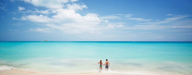 Paar auf Antigua läuft vom Strand ins Meer