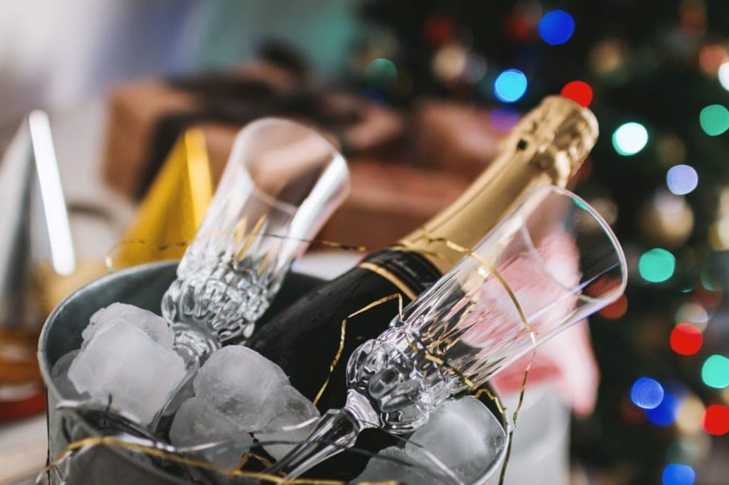 Flasche Champagner und Gläser in einem mit Eiswürfel befüllten Kübel
