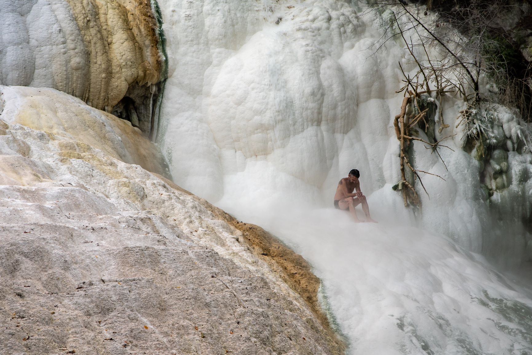 Mann unter Wasserfall in Bagni San Filippo