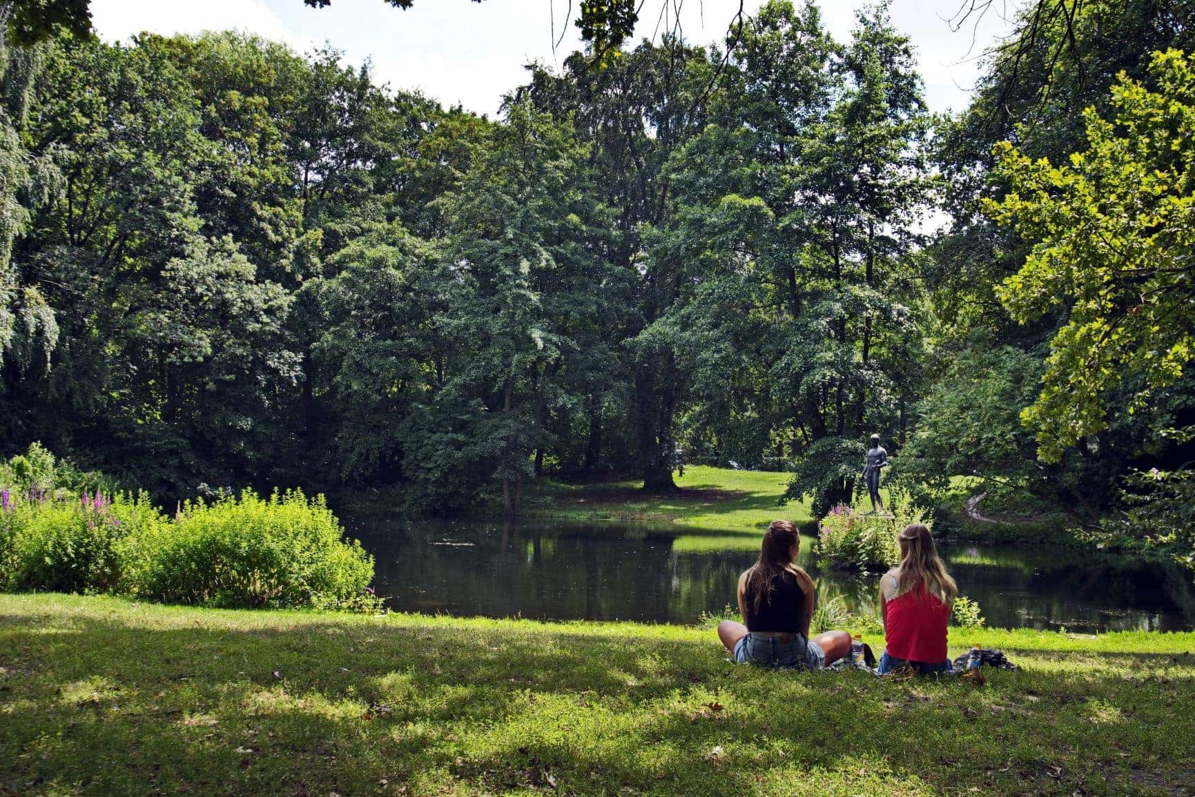 Zwei Frauen sitzen im Berliner Tiergarten am See