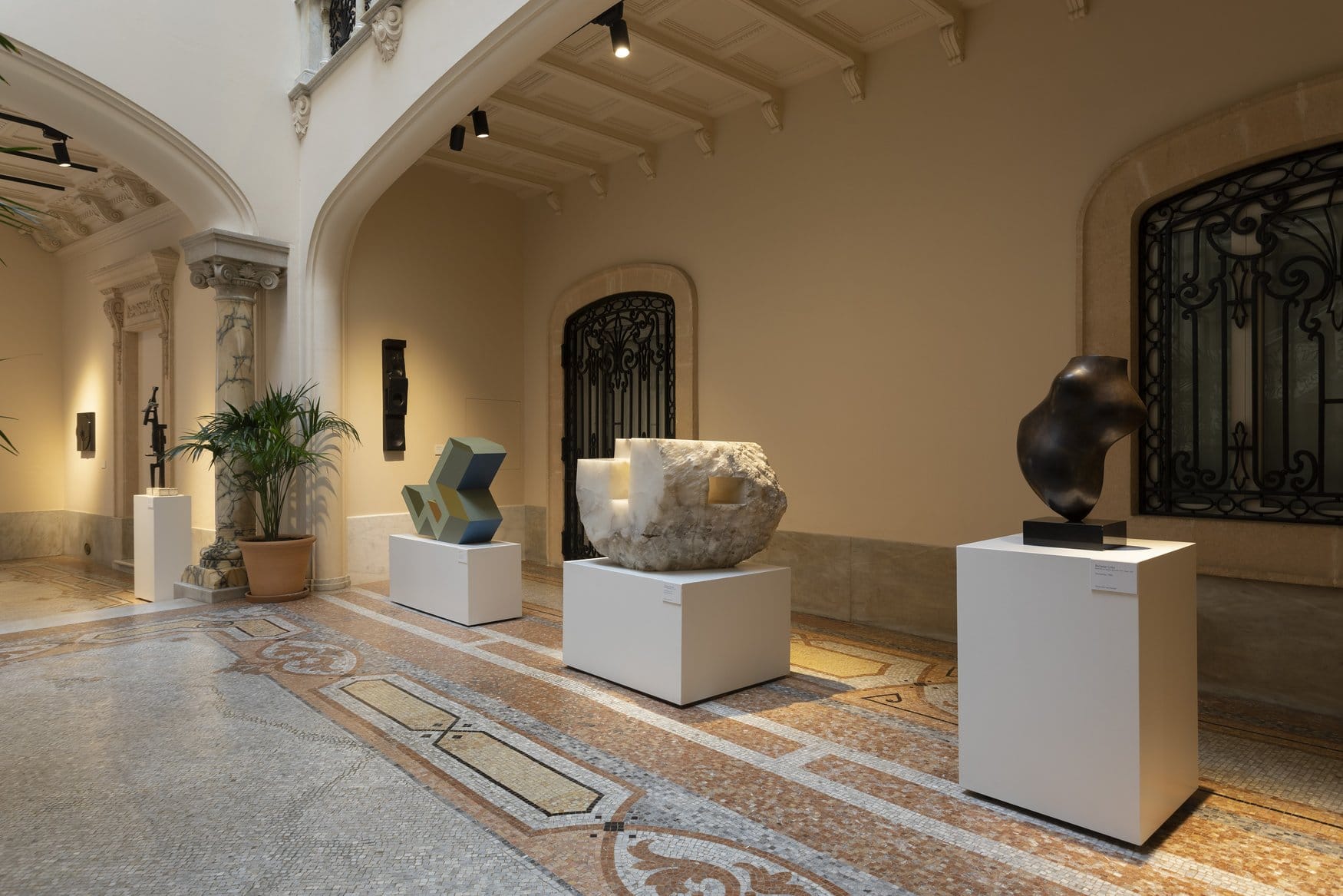 Ausstellungsraum mit vier Skulpturen auf weißen Sockeln, Mosaikboden und schmiedeeisernen Gittern im Museu Fundación Juan March in Palma.