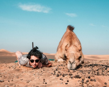 Frau und Kamel auf Boden liegend in der Wüste