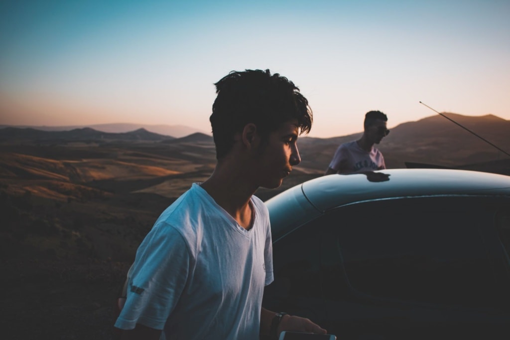 Zwei junge Männer steigen in Auto ein, Hintergrund Mond-Landschaft