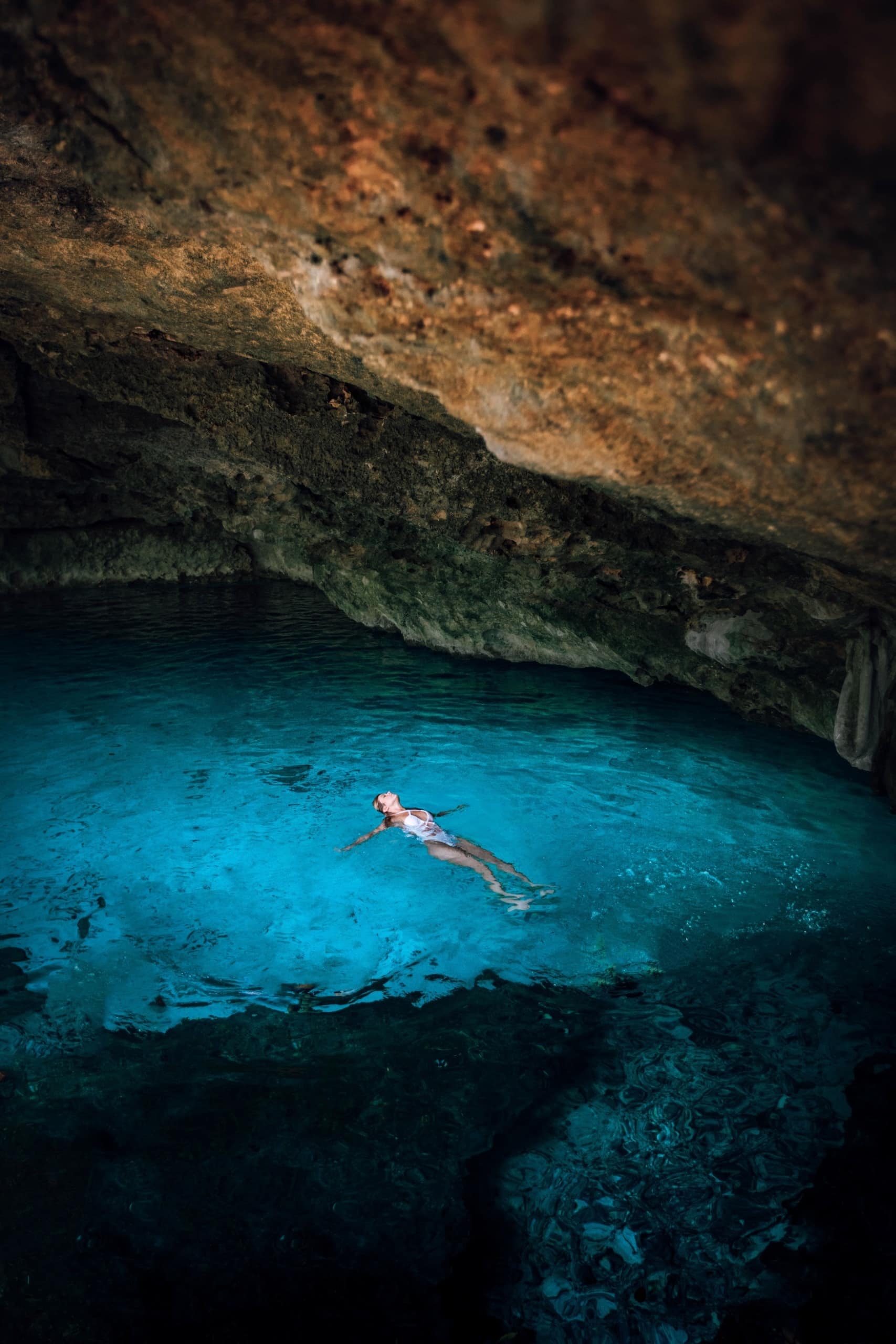 Frau schwimmt auf dem Rücken in Cenote in Mexiko