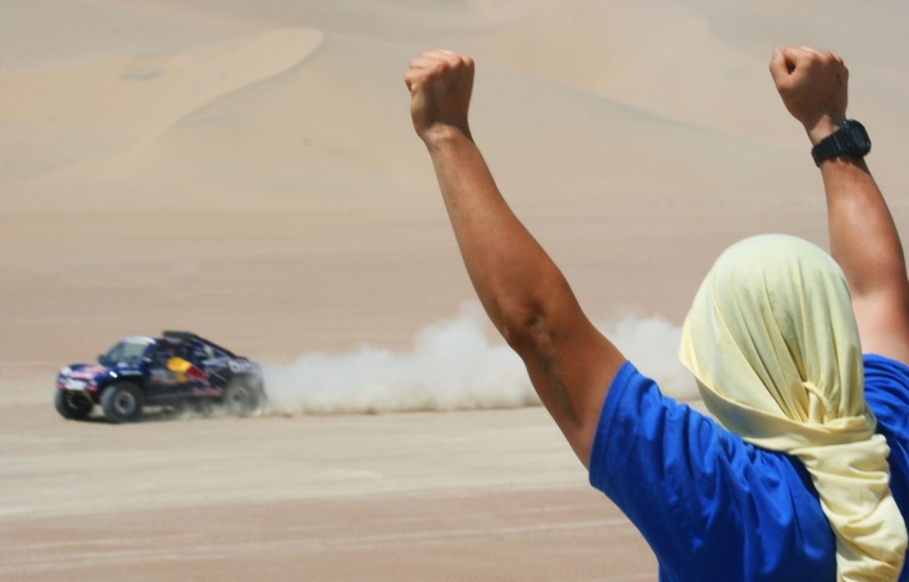 Zuschauer jubelt einem vorbeifahrenden Auto bei der Rally Dakar zu