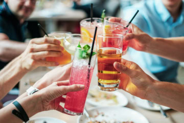 Freunde stoßen mit Cocktails an.