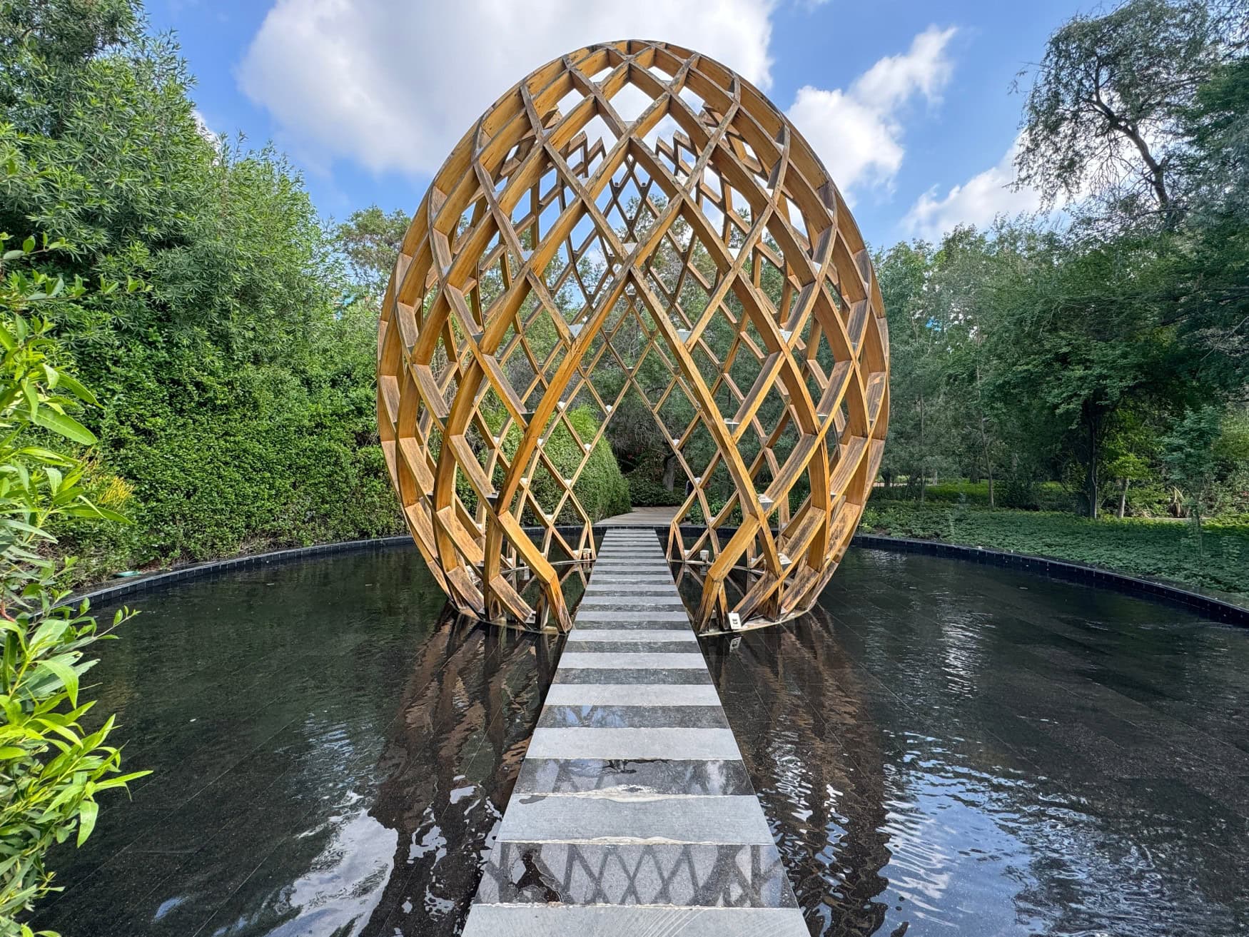 Eine Kunstinstallation auf der Insel Al Noor in Sharjah; ein Steg führt über einem Teich zu einem aus metallbögen gewobenen Ei