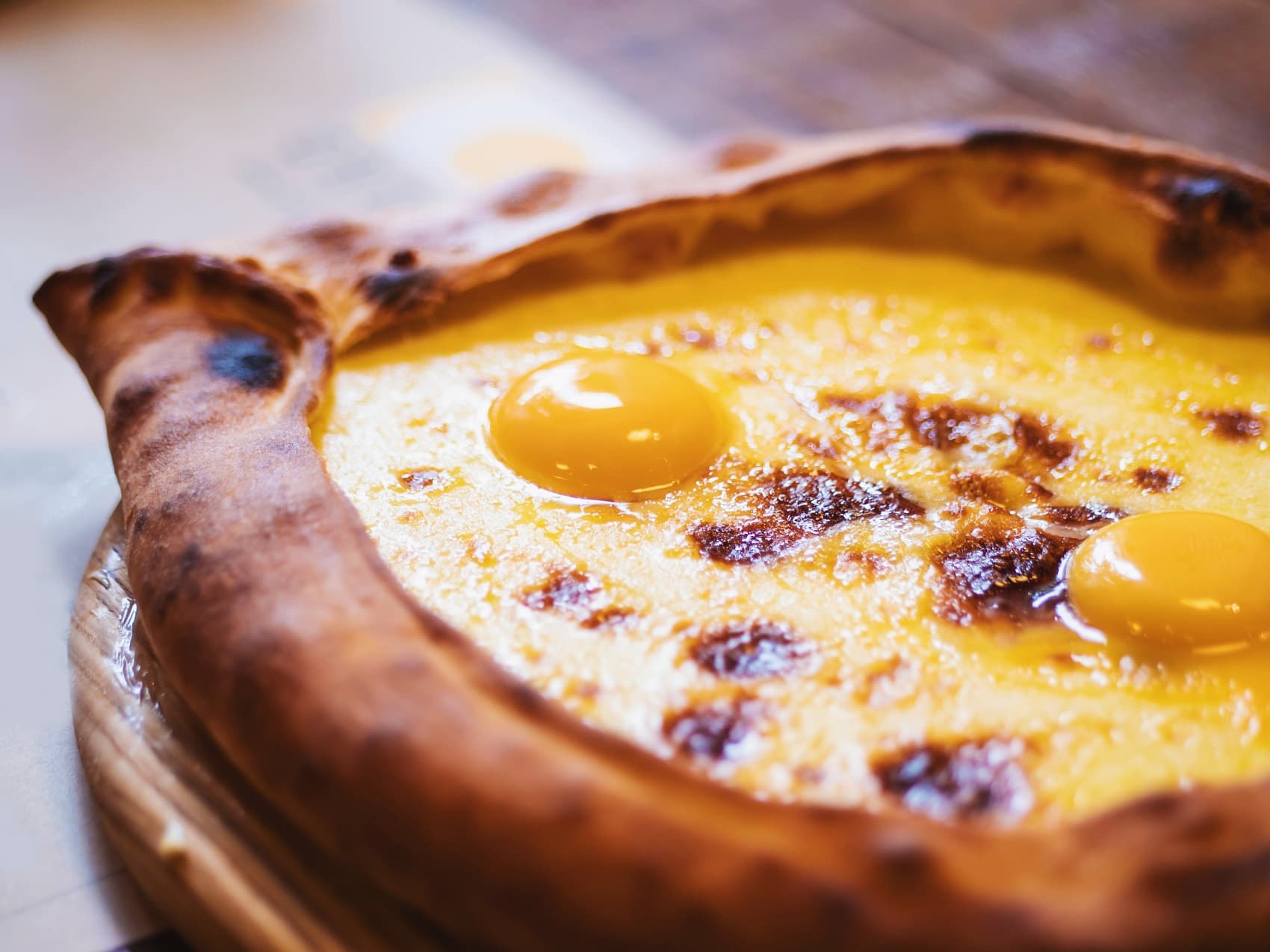 Nahansicht eines georgischen Khachapuri, einem mit zwei Eiern und Käse gefüllten Teigschiffchen