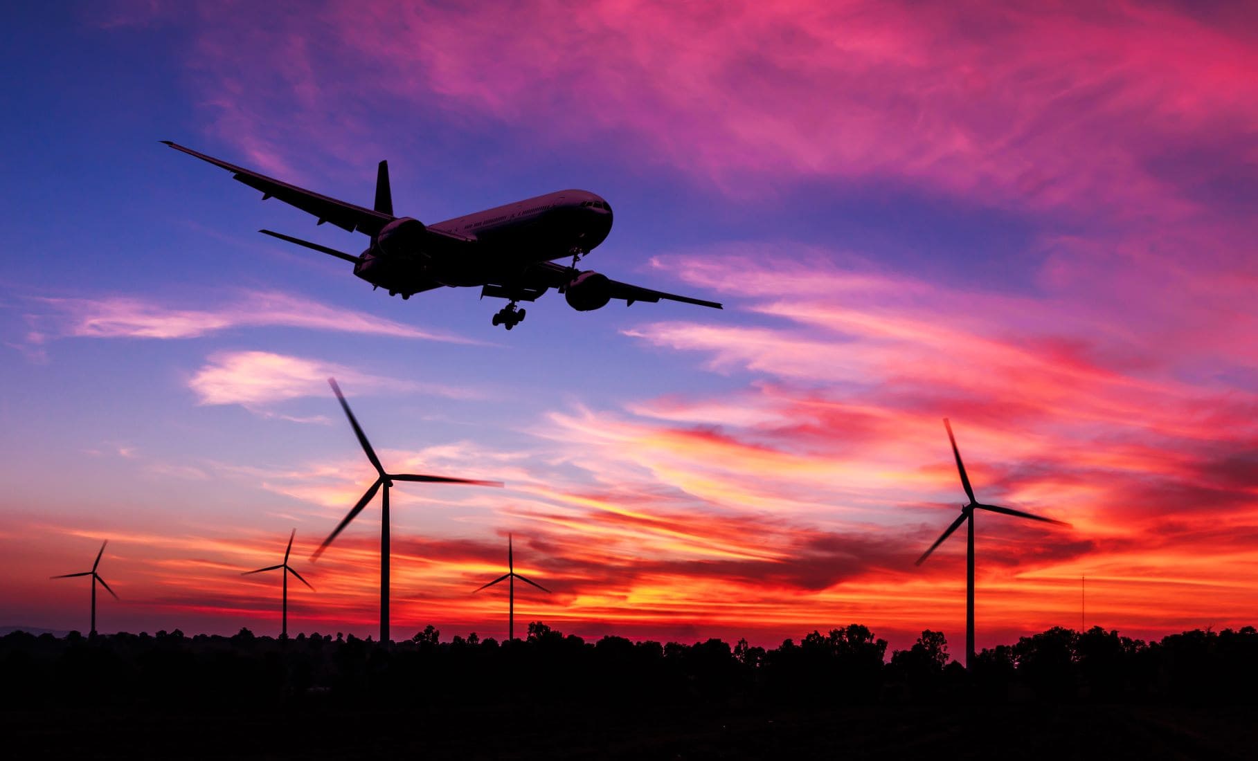 Flugzeug landet, im Hintergrund Windräder