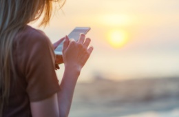 Frau nutzt Handy am Strand
