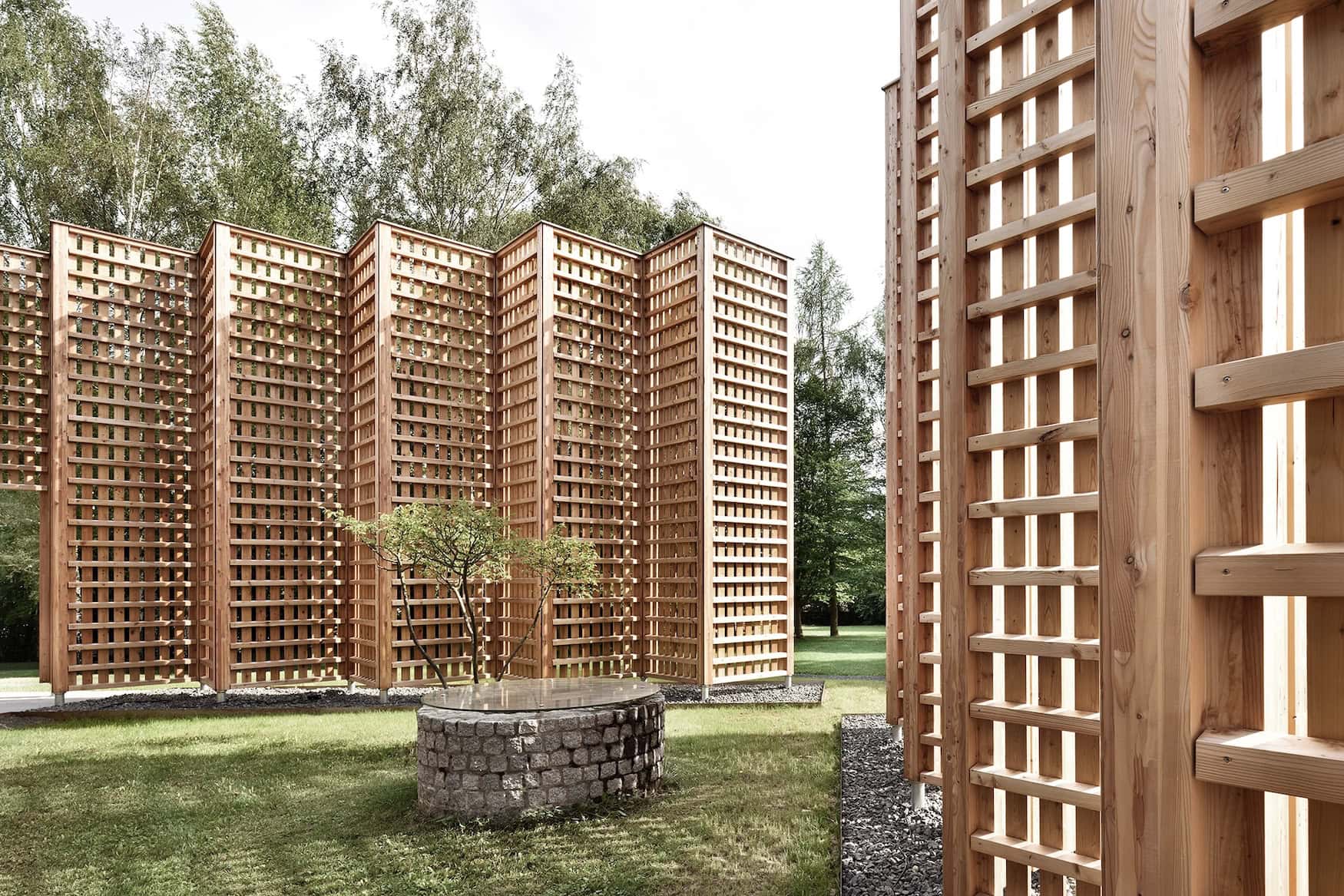 Holzgitterparavents des Biohotels Sturm im Garten mit Ahorn und Natursteinbrunnen