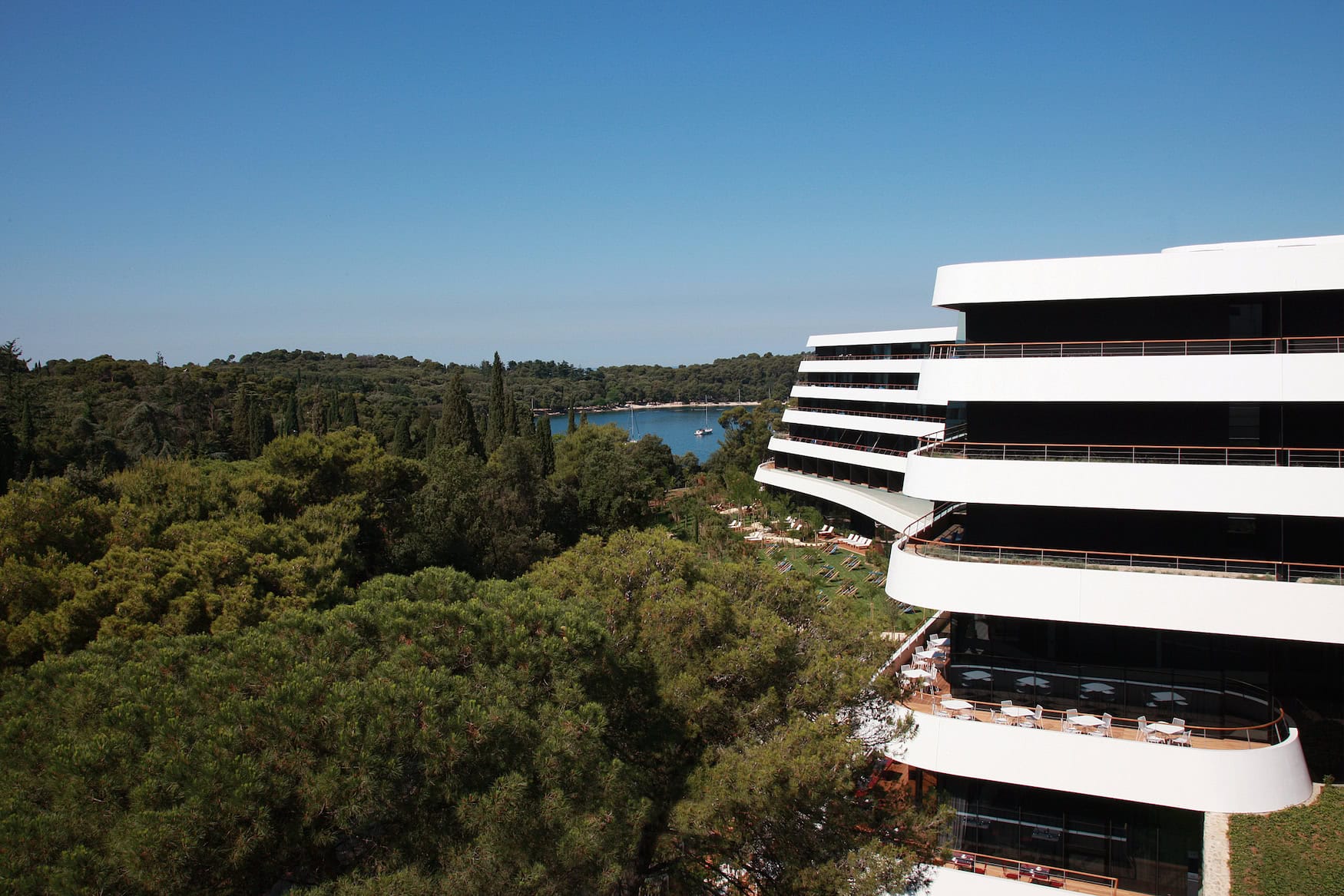 Geschwungene weiße Etagen des Lone Hotels in Rovinj mit Blick über den Pinienwald auf die Bucht