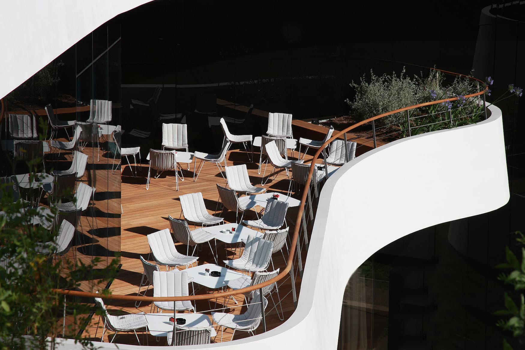 Geschwungene Sonnenterrasse des Lone Hotels in Rovinj mit weißen Stühlen und Holzdeck