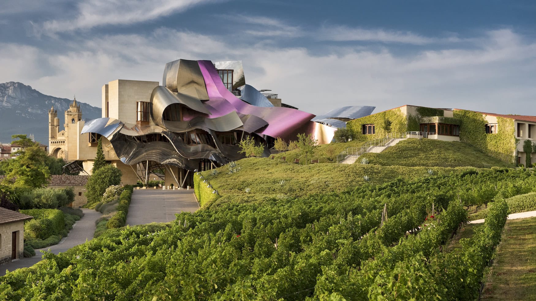 Titanfassade des Marqués de Riscal von Frank Gehry über den Weinbergen der Rioja mit Bergkulisse