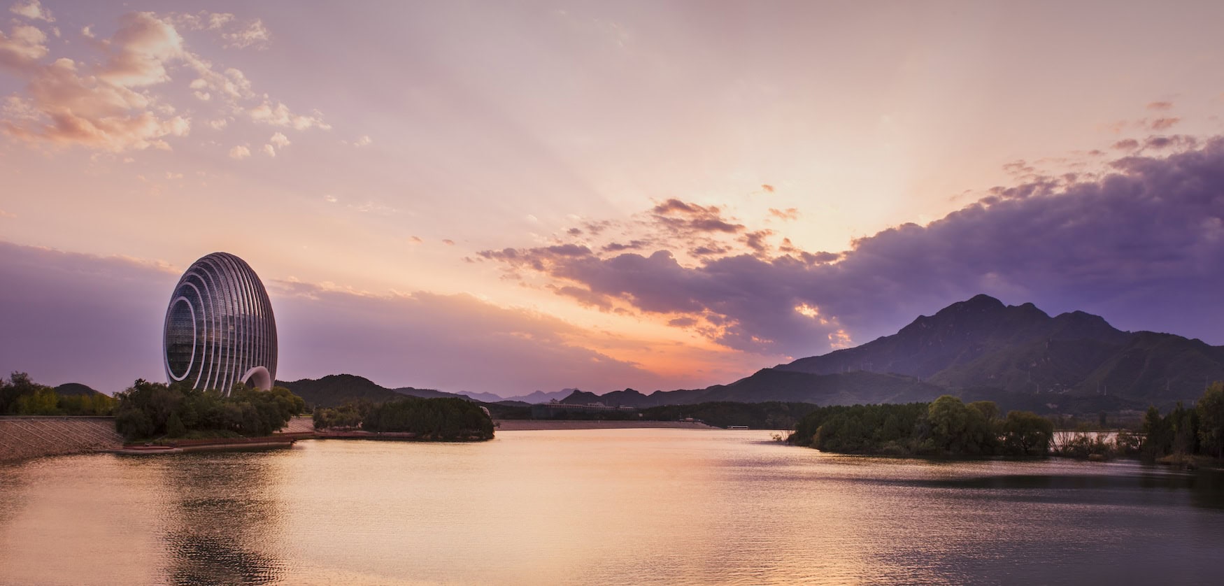 Kugelförmiges Sunrise Kempinski am Yanqi-See bei Peking mit Bergkulisse im Abendlicht