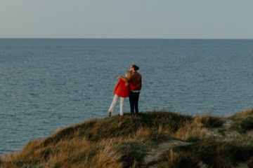 Ein Mann und eine Frau stehen auf einer Düne und schauen auf die Nordsee.