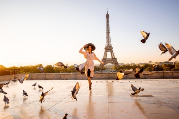 Frau posiert in die Kamera vor Eiffelturm in Paris während Sonnenuntergang