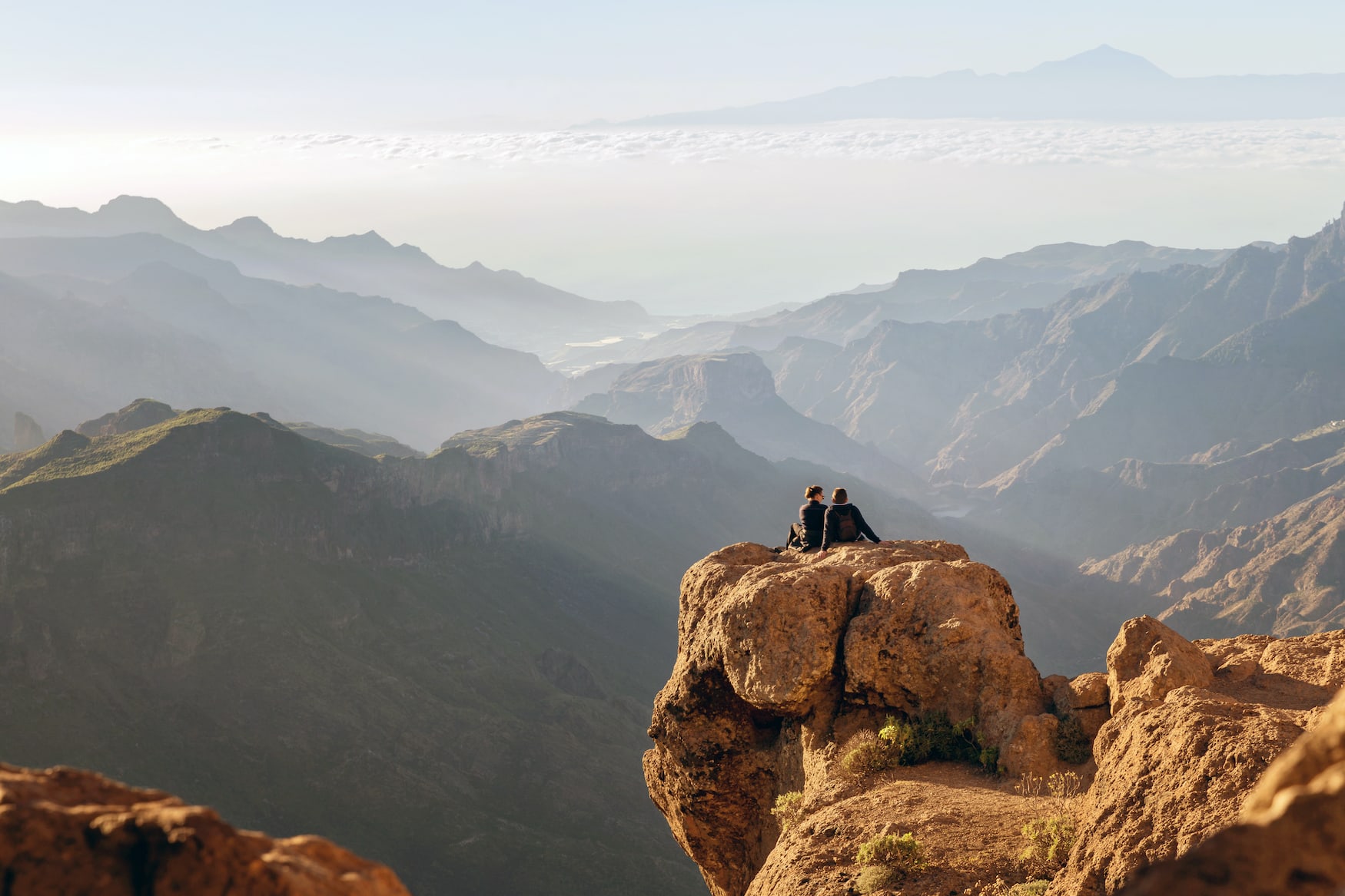 Pärchen sitzt auf Felsen und blickt über Gran Canaria