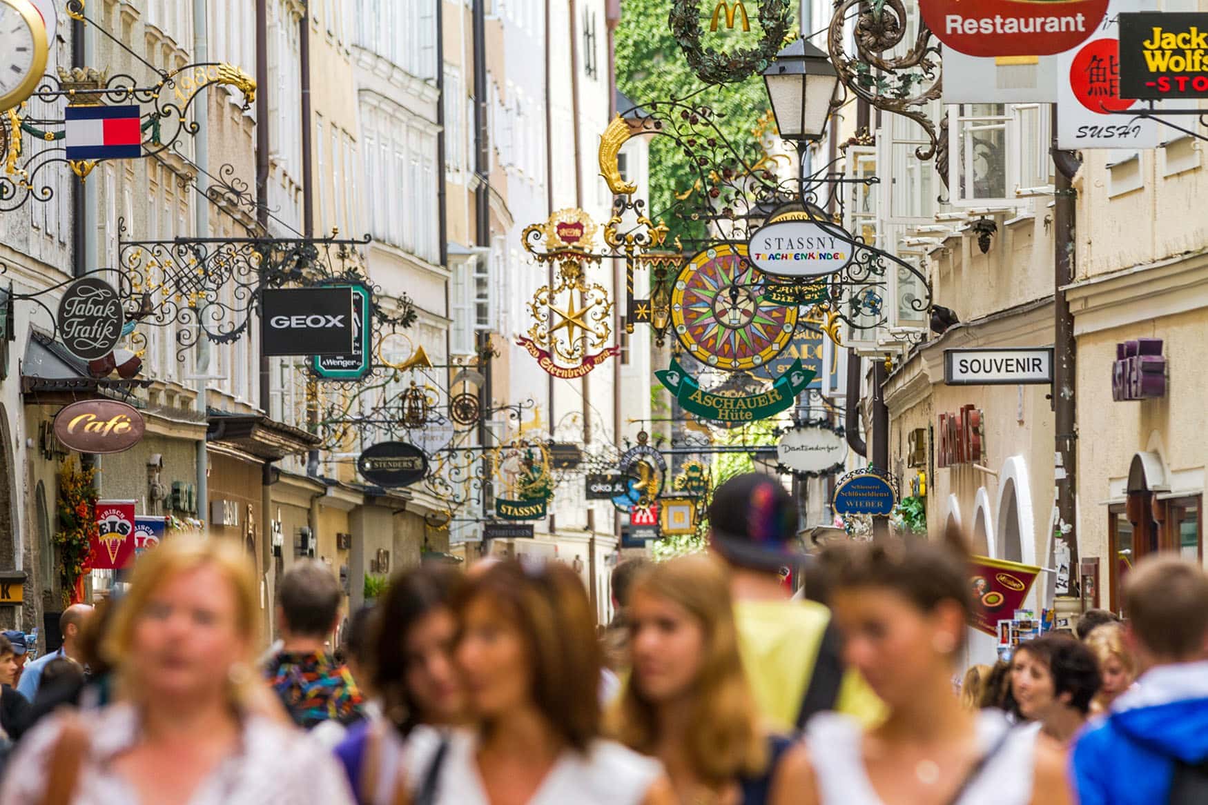 Menschen in der Getreidegasse in Salzburg über ihnen Schilder der Shops