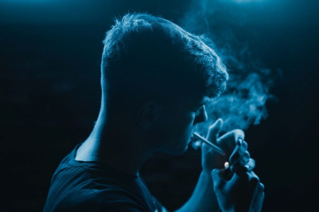 Junger Mann zündet sich eine Zigarette an