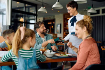 Familie bezahlt mit Kreditkarte kontaktlos im Restaurant in den USA.