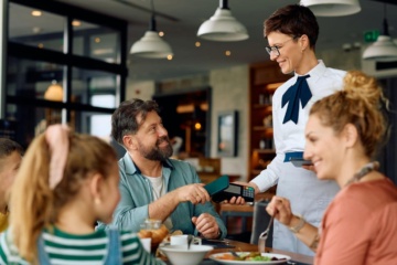 Familie bezahlt mit Kreditkarte kontaktlos im Restaurant in den USA.