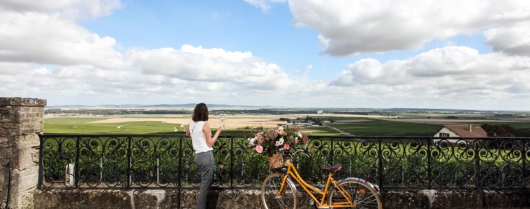 Frau mit Fahrrad trinkt Glas Champagner in der Champagne