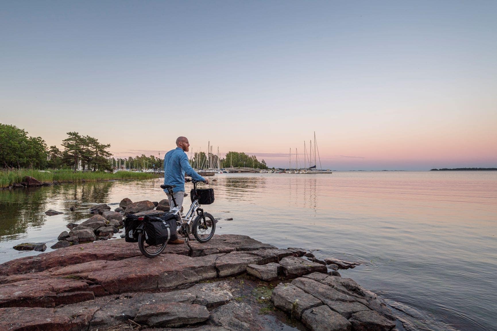 Mann steht mit seinem Fahrrad am See und blickt in die Weite