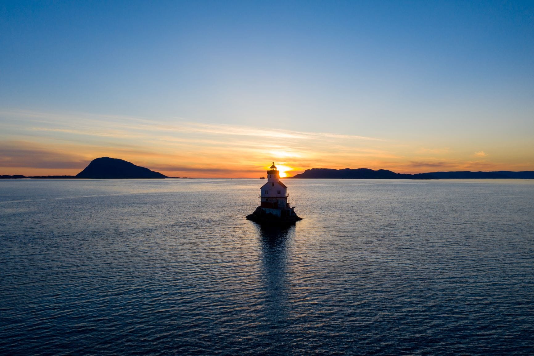 Leuchtturm Stabben in Norwegen, mitten im Meer; hinter dem Leuchtturm geht die Sonne unter