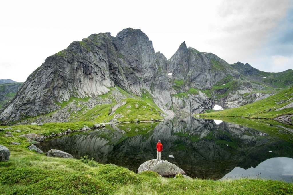 Norwegen Natur: Ein Mann steht vor einem See in den Lofoten 