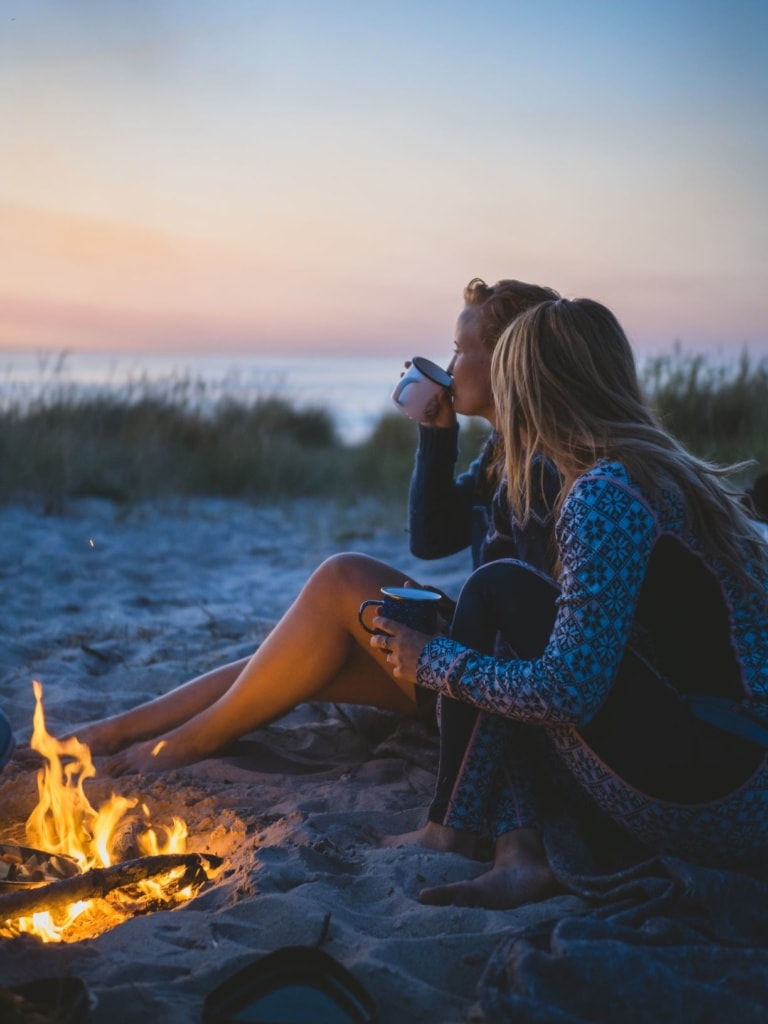 Zwei junge Frau sitzen an einem Lagerfeuer in Dänemark 