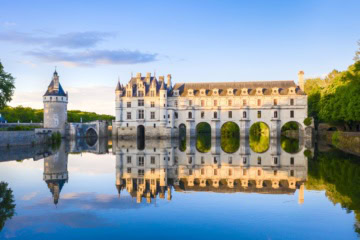 Blick auf das Chateau de Chenonceau im Loiretal, vom Schlossteich aus, in dem sich das Schloss im Licht der Abendsonne spiegelt.