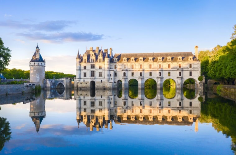 Blick auf das Chateau de Chenonceau im Loiretal, vom Schlossteich aus, in dem sich das Schloss im Licht der Abendsonne spiegelt.