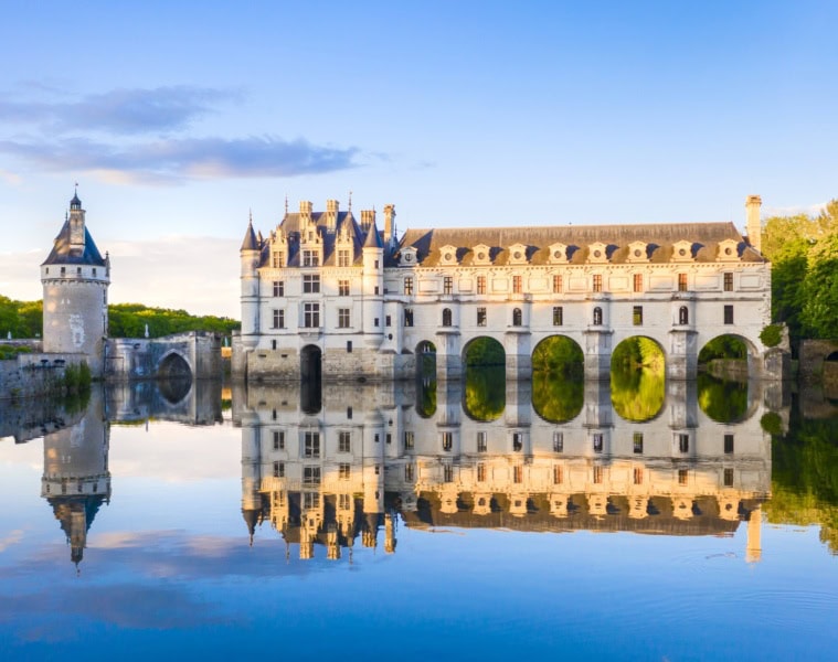 Blick auf das Chateau de Chenonceau im Loiretal, vom Schlossteich aus, in dem sich das Schloss im Licht der Abendsonne spiegelt.