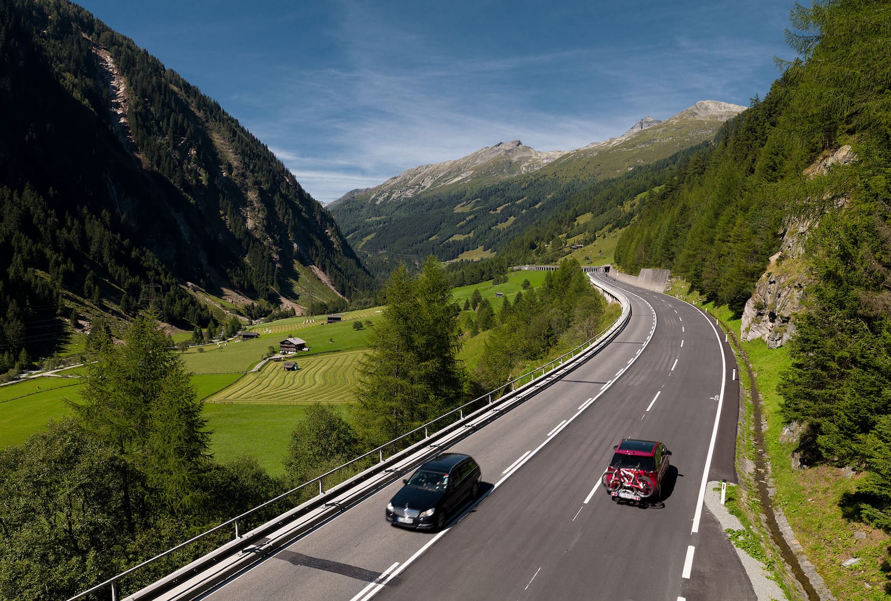 Autos fahren auf der Felbertauernstraße zwischen Bergpanorama der Alpen