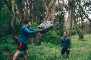 Zwei Männer in Wald werfen sich Travel Bag von Peak Design zu