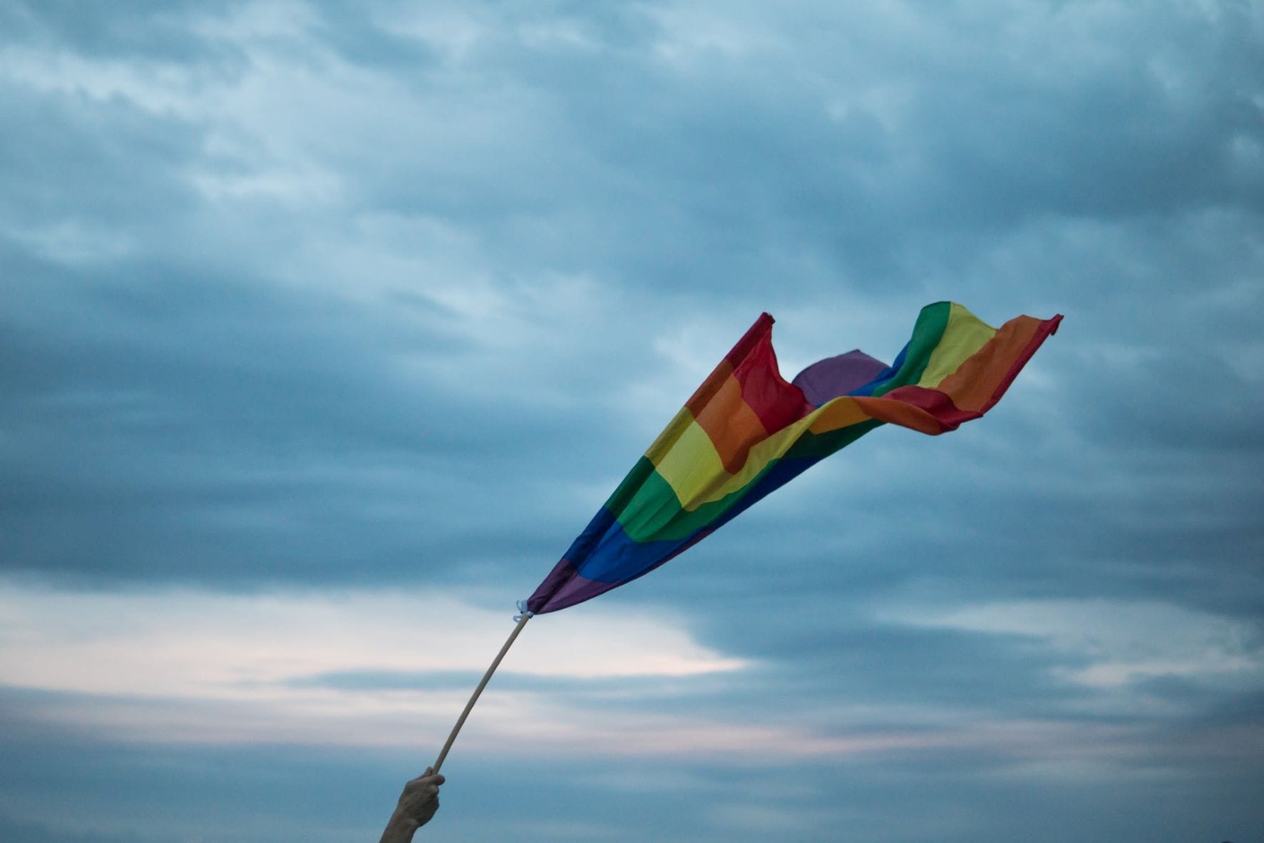 Person hält Regenbogen-Flagge in die Luft 