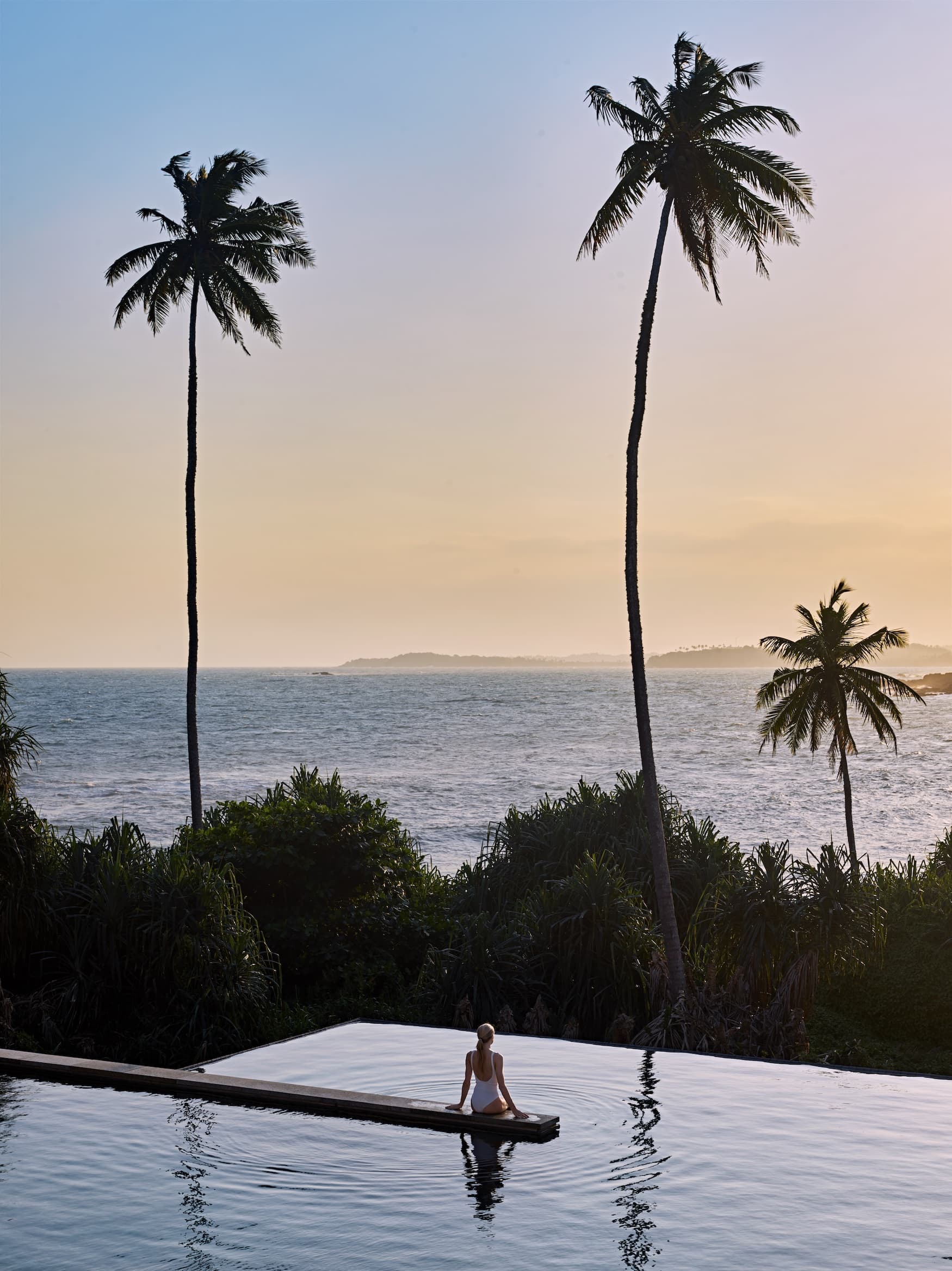 Frau sitzt in Pool und blickt auf Küste vor Sri Lanka