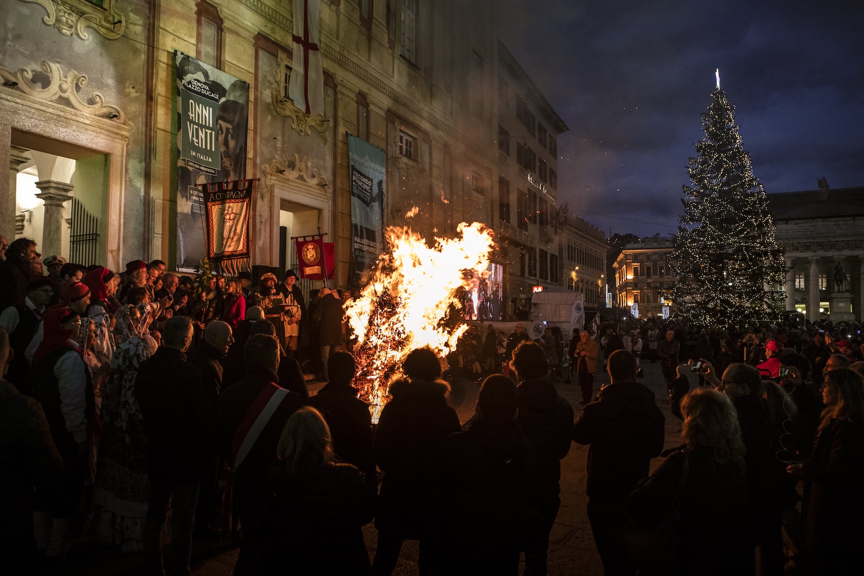 Menschen stehen um Feuer vor einer Kirche in Genua im Winter beim Confuego Ritual