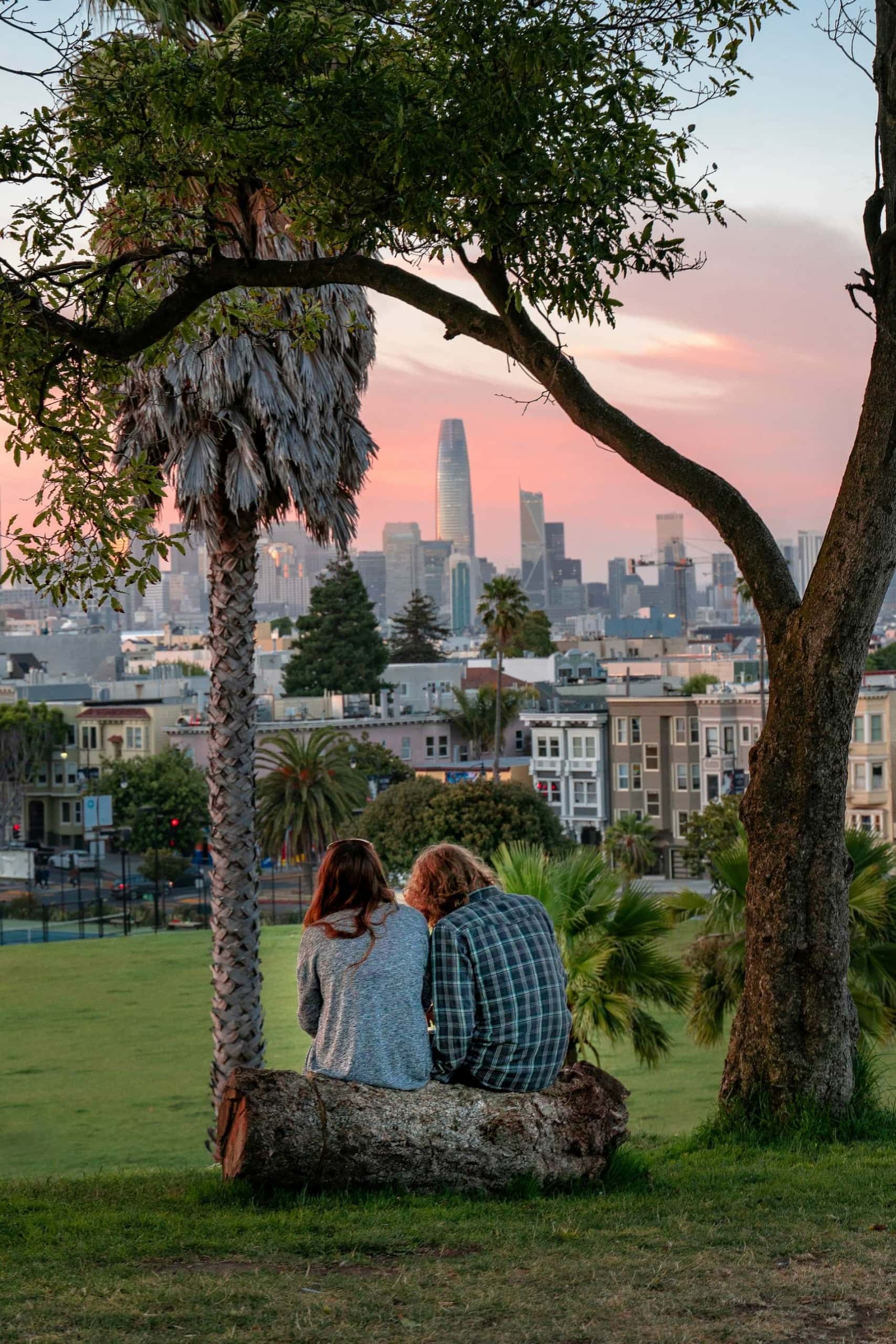 Mann und Frau sitzen auf Baumstamm im Dolores Park, San Francisco 