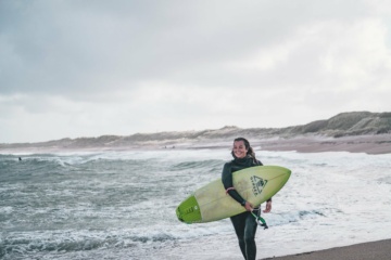 Frau surft in Klitmøller, Dänemark