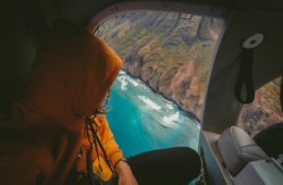 Mann blickt aus Flugzeugfenster auf Meeresbucht
