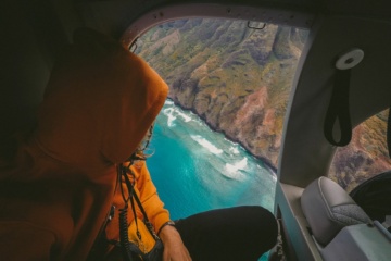 Mann blickt aus Flugzeugfenster auf Meeresbucht