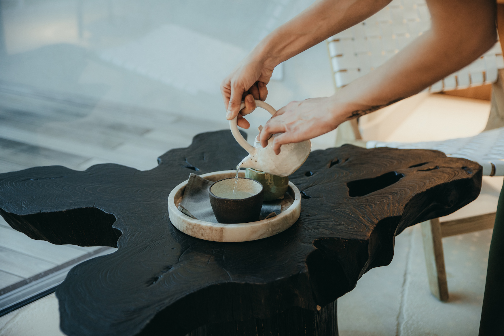Frau schenkt Grünen Tee in Keramiktassen ein