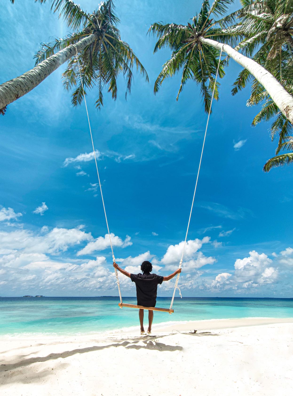 Junge schaukelt zwischen zwei Palmen auf den Malediven 
