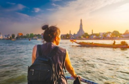 Touristin in Thailand auf einem Schiff, blickt zum Ufer