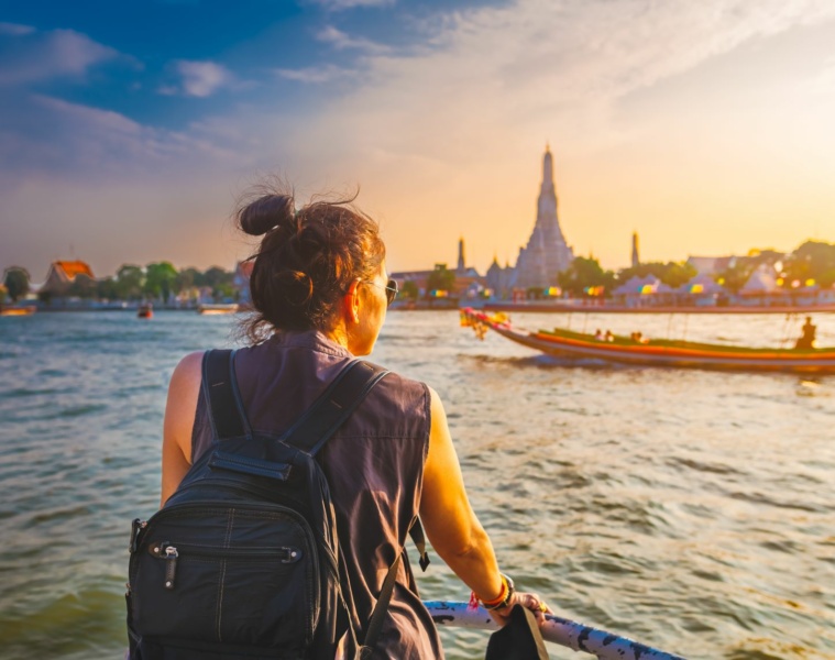 Touristin in Thailand auf einem Schiff, blickt zum Ufer