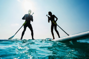 Zwei Urlauber stehen auf ihren Stand-Up-Paddleboards